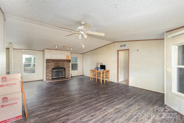 living room featuring wood finished floors, lofted ceiling, a textured ceiling, a ceiling fan, and a fireplace