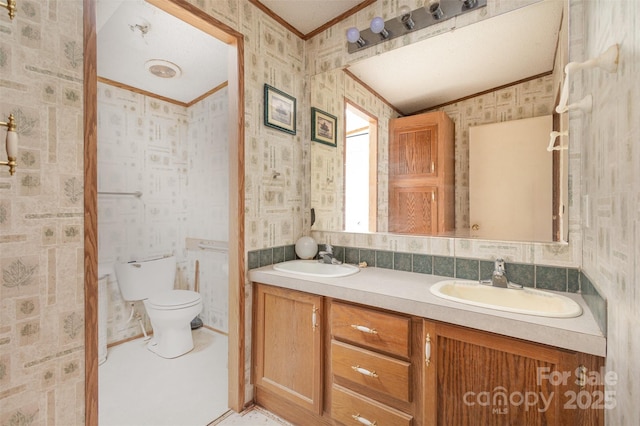 full bathroom featuring crown molding, wallpapered walls, toilet, and double vanity