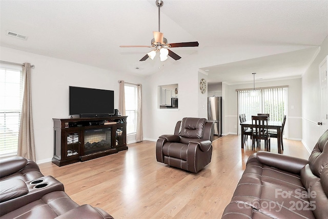 living room with light wood finished floors, ceiling fan, lofted ceiling, and baseboards