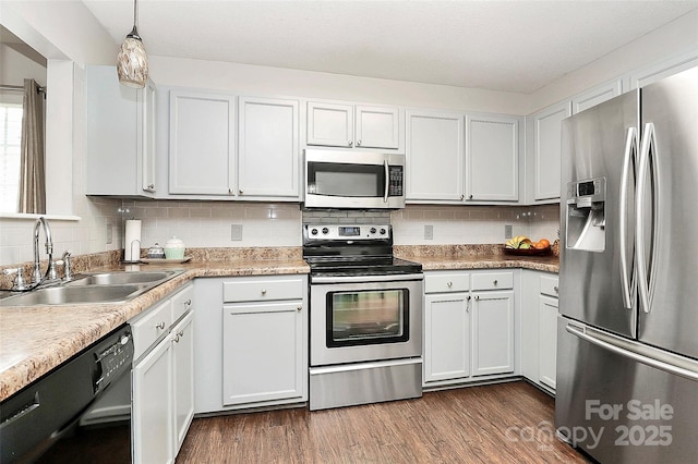 kitchen featuring appliances with stainless steel finishes, a sink, decorative backsplash, and dark wood finished floors
