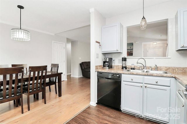 kitchen featuring black dishwasher, a sink, wood finished floors, light countertops, and decorative light fixtures