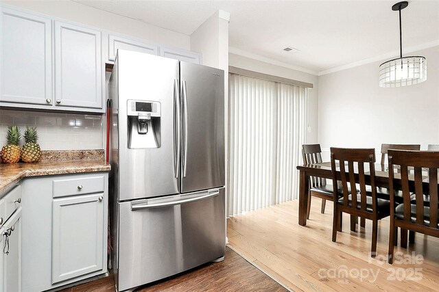 kitchen with stainless steel fridge with ice dispenser, tasteful backsplash, wood finished floors, crown molding, and hanging light fixtures