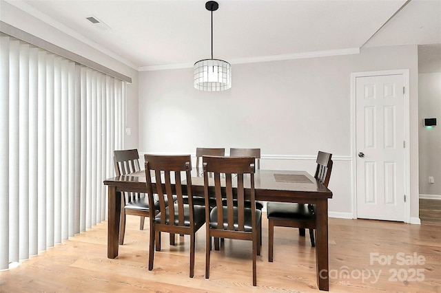 dining room with light wood finished floors, ornamental molding, and baseboards