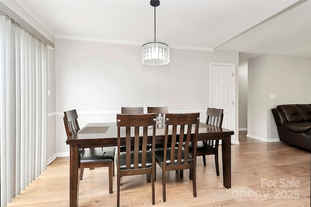 dining space featuring light wood-type flooring, crown molding, and baseboards