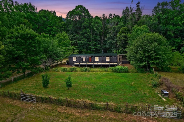 view of front of house with a wooden deck and a view of trees
