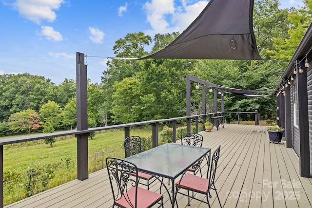 wooden deck with a lawn and outdoor dining area