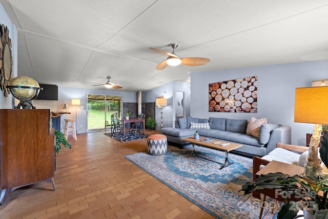 living area with a ceiling fan and brick patterned floors