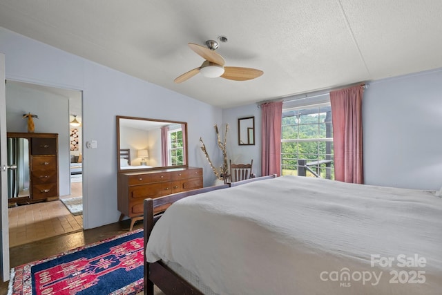 bedroom with multiple windows, vaulted ceiling, a ceiling fan, and a textured ceiling