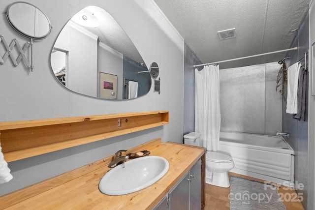 bathroom featuring a textured ceiling, shower / bath combination with curtain, toilet, and vanity