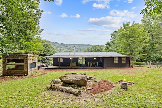 back of property featuring an outdoor fire pit, a yard, metal roof, and a patio area