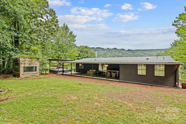 back of property with a patio, a lawn, and metal roof