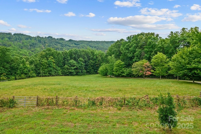 view of yard featuring a view of trees, fence, and a view of countryside