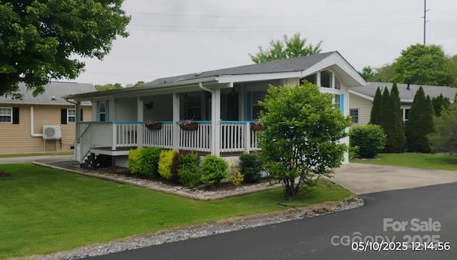 view of front facade with a porch, a cooling unit, a front lawn, and driveway