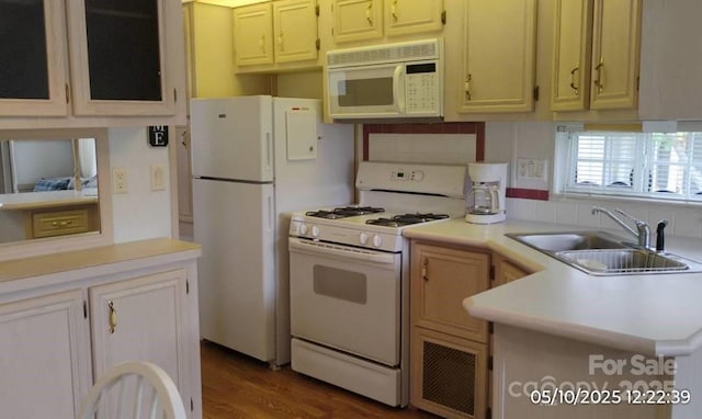 kitchen featuring white appliances, a sink, light countertops, dark wood-type flooring, and a peninsula