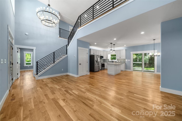 68 Bamboo Trl, Candler, NC 28715 - unfurnished living room featuring a chandelier, baseboards, stairway, healthy amount of natural light, and recessed lighting