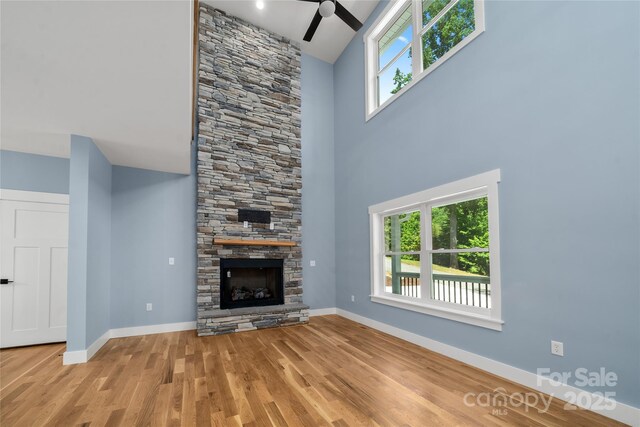 68 Bamboo Trl, Candler, NC 28715 - unfurnished living room featuring ceiling fan, wood finished floors, baseboards, plenty of natural light, and a towering ceiling