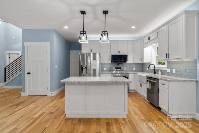 68 Bamboo Trl, Candler, NC 28715 - kitchen with appliances with stainless steel finishes, a kitchen island, backsplash, white cabinets, and light wood-style floors