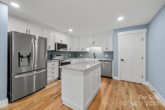 68 Bamboo Trl, Candler, NC 28715 - kitchen featuring appliances with stainless steel finishes, a sink, white cabinets, backsplash, and a kitchen island