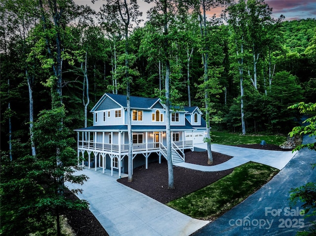 68 Bamboo Trl, Candler, NC 28715 - view of front of home featuring driveway, covered porch, an attached garage, and a forest view