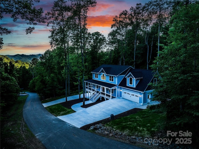 68 Bamboo Trl, Candler, NC 28715 - view of front of home with concrete driveway, a garage, a porch, and a wooded view
