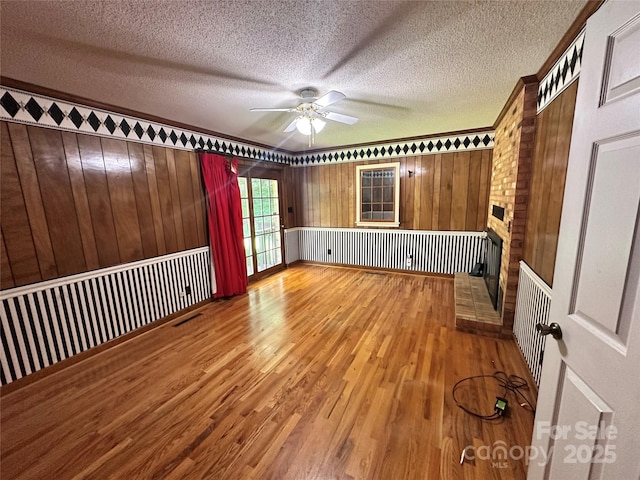 5495 Valley Run St, Hickory, NC 28601 - unfurnished room featuring a ceiling fan, wood finished floors, a textured ceiling, a fireplace, and wood walls
