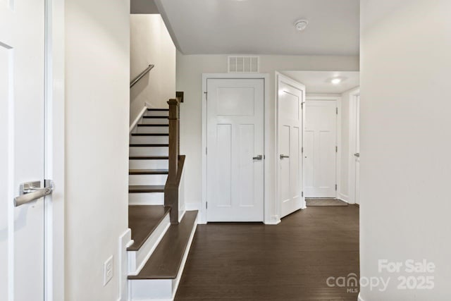hall featuring dark wood-style flooring, stairway, and baseboards