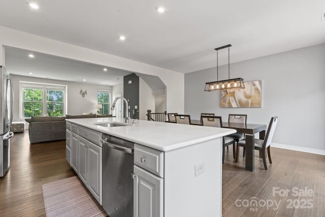 kitchen featuring appliances with stainless steel finishes, a sink, open floor plan, dark wood-style flooring, and recessed lighting