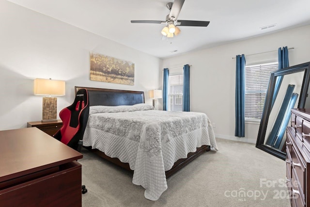 bedroom featuring light carpet, a ceiling fan, and baseboards