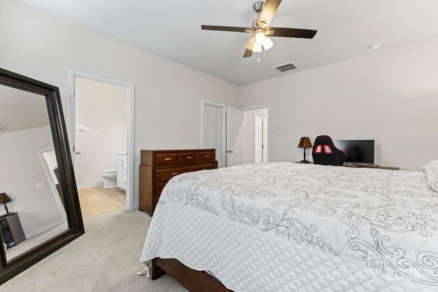 bedroom featuring light carpet, ensuite bathroom, and ceiling fan