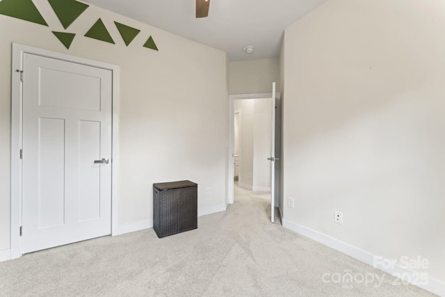 unfurnished bedroom featuring light colored carpet, baseboards, and a ceiling fan