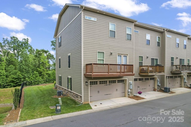 view of front of house with an attached garage, a front yard, central AC, and board and batten siding