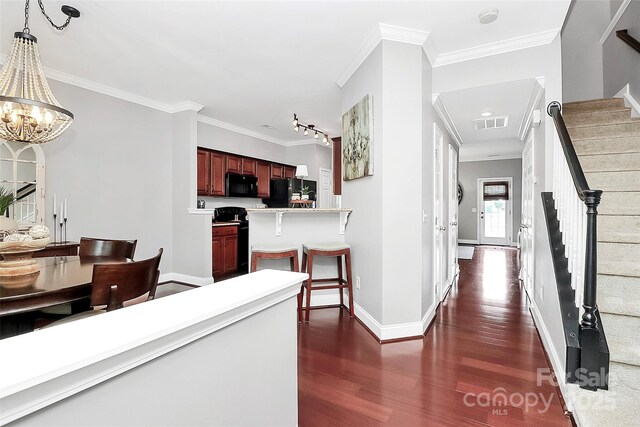 10378 Alexander Martin Ave, Charlotte, NC 28277 - hall with dark wood finished floors, stairs, ornamental molding, baseboards, and a chandelier
