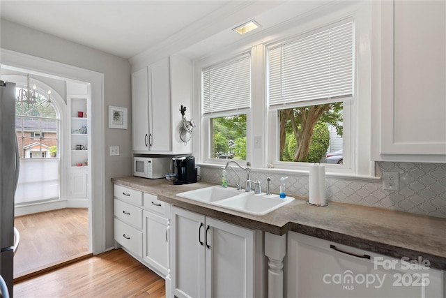 415 Norwood St SW, Lenoir, NC 28645 - kitchen featuring white microwave, backsplash, a sink, and white cabinetry