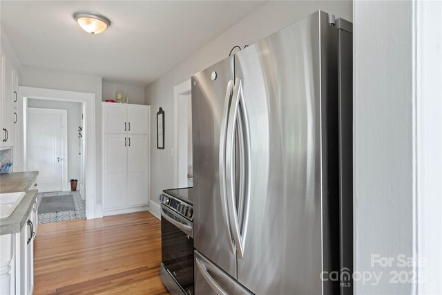 415 Norwood St SW, Lenoir, NC 28645 - kitchen featuring appliances with stainless steel finishes, white cabinets, light countertops, light wood finished floors, and baseboards