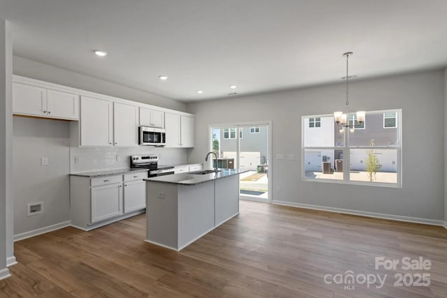 kitchen featuring appliances with stainless steel finishes, a sink, a chandelier, white cabinets, and tasteful backsplash