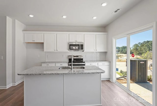 kitchen featuring stainless steel appliances, light wood-style flooring, white cabinetry, light stone countertops, and recessed lighting