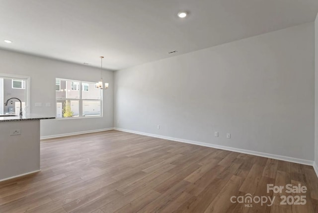 unfurnished dining area featuring a chandelier, wood finished floors, baseboards, and recessed lighting