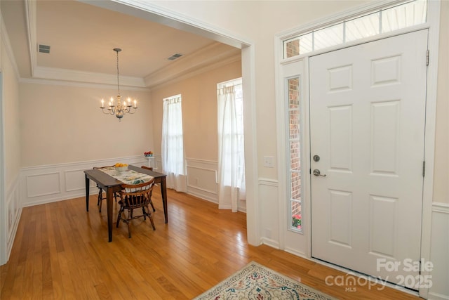 6310 Highland Commons Rd, Charlotte, NC 28269 - dining space with a chandelier, ornamental molding, a decorative wall, light wood-type flooring, and wainscoting