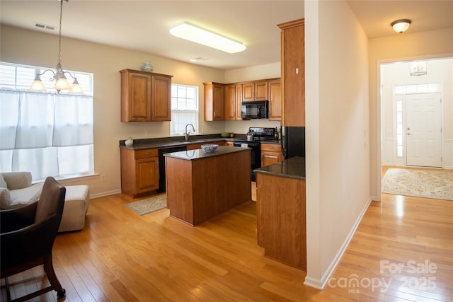 6310 Highland Commons Rd, Charlotte, NC 28269 - kitchen with black appliances, light wood-style floors, a kitchen island, brown cabinetry, and a chandelier