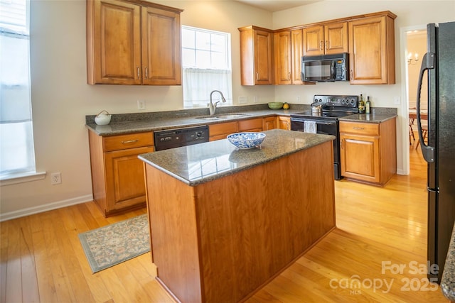 6310 Highland Commons Rd, Charlotte, NC 28269 - kitchen featuring black appliances, a sink, light wood-style flooring, brown cabinetry, and a center island