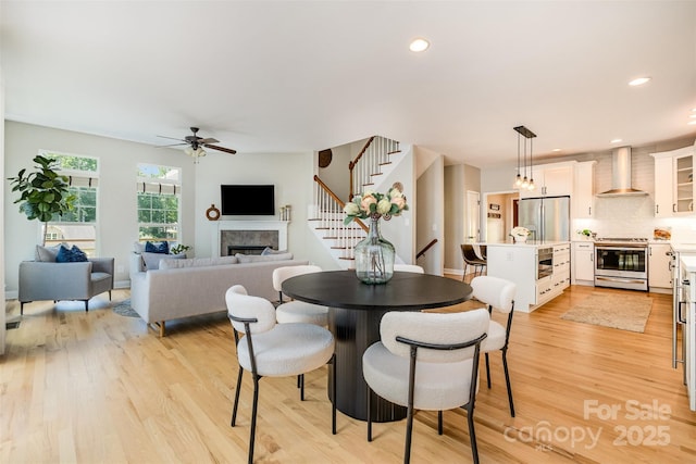 2845 Lakefront Dr, Belmont, NC 28012 - dining room with stairway, a ceiling fan, light wood-style flooring, a fireplace, and recessed lighting
