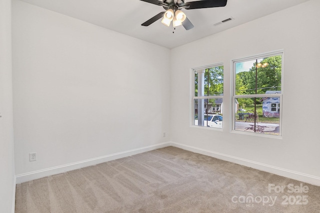 spare room featuring light colored carpet, baseboards, and ceiling fan