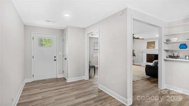 7860 Henry Harris Rd, Fort Mill, SC 29707 - foyer with light wood-style floors, a fireplace with raised hearth, baseboards, and ornamental molding