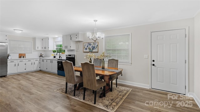 7860 Henry Harris Rd, Fort Mill, SC 29707 - dining area with a chandelier, light wood-type flooring, crown molding, and baseboards
