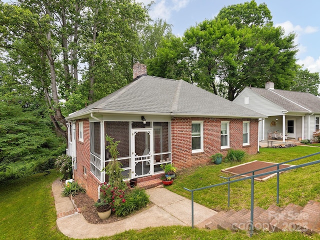5 Enka Oak St, Candler, NC 28715 - view of front of property featuring a sunroom, brick siding, a front lawn, a shingled roof, and a chimney