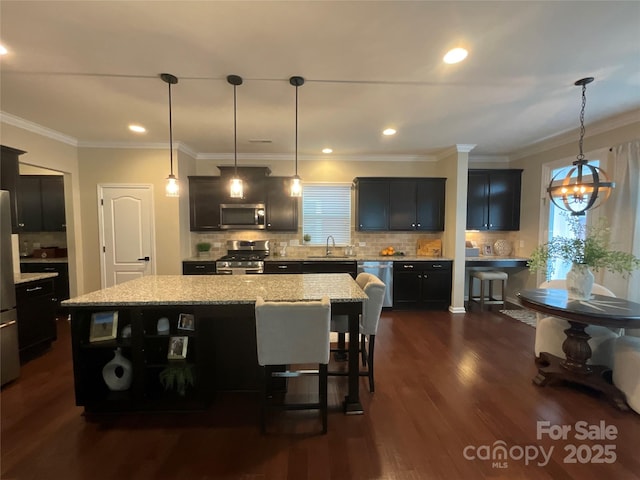 kitchen with stainless steel appliances, a sink, plenty of natural light, backsplash, and ornamental molding
