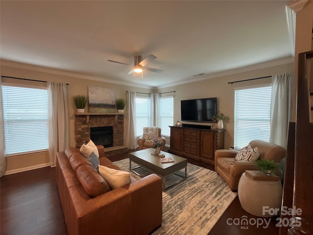 living area featuring dark wood-type flooring, a ceiling fan, a fireplace, ornamental molding, and baseboards