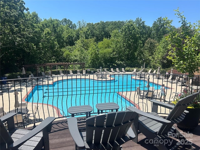 community pool with a patio area and fence