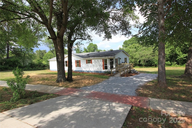 single story home featuring driveway, a front yard, and a wooden deck
