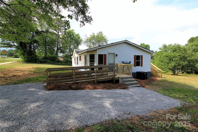 view of front of property with central air condition unit, a wooden deck, and a front lawn